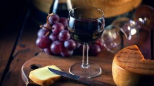 Un maridaje clásico: una copa de merlot acompañada de un trozo de gouda añejo, resaltando la combinación perfecta entre el vino tinto y el queso maduro.